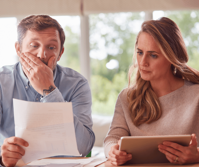 Concerned couple reviewing paper and tablet