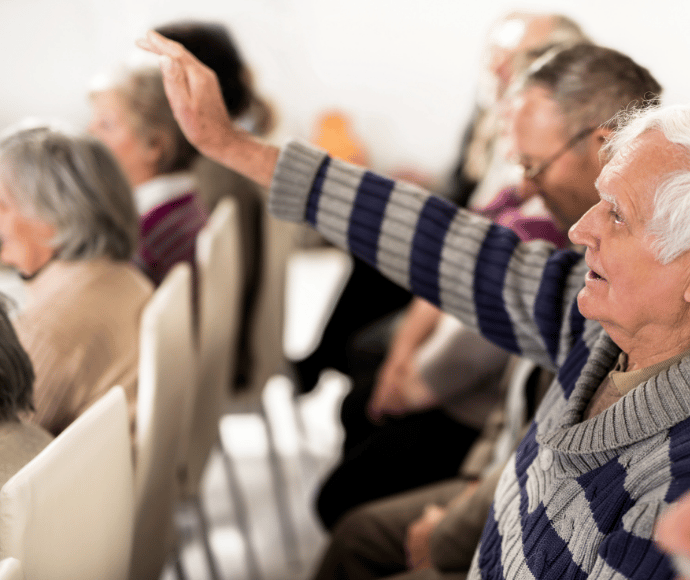Old man raising his hand to ask a question