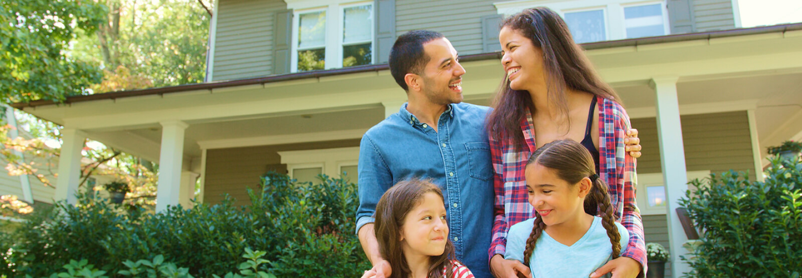 Family of four outside two-story home
