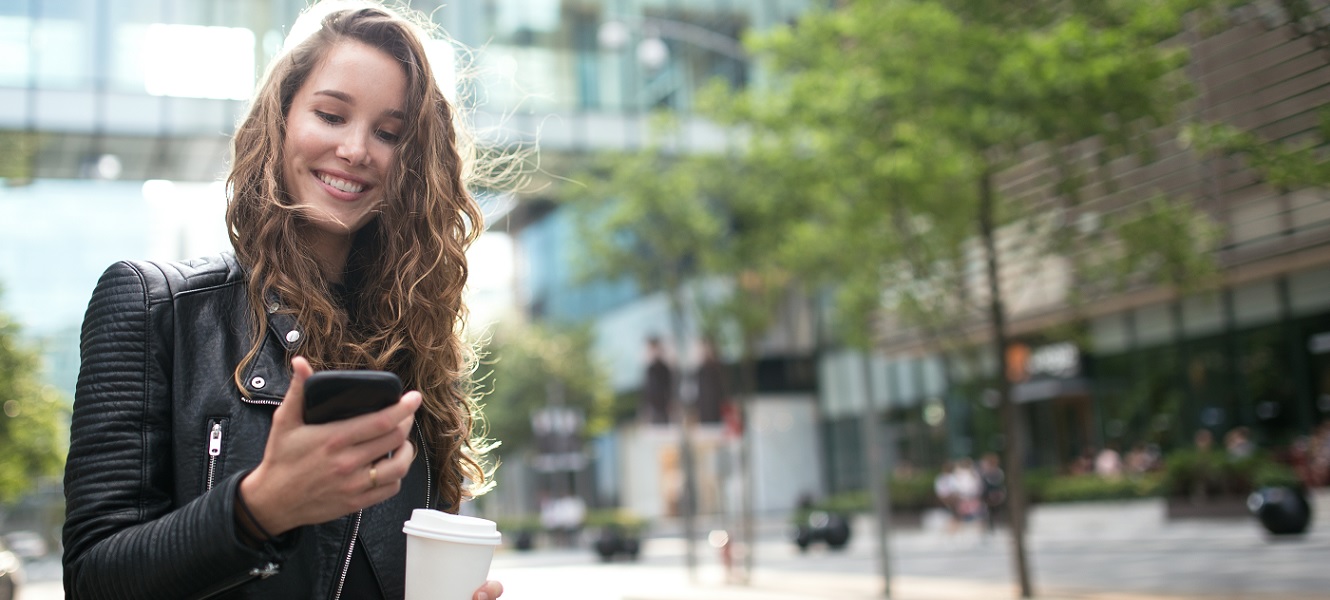 young woman on the go using mobile phone to do her banking